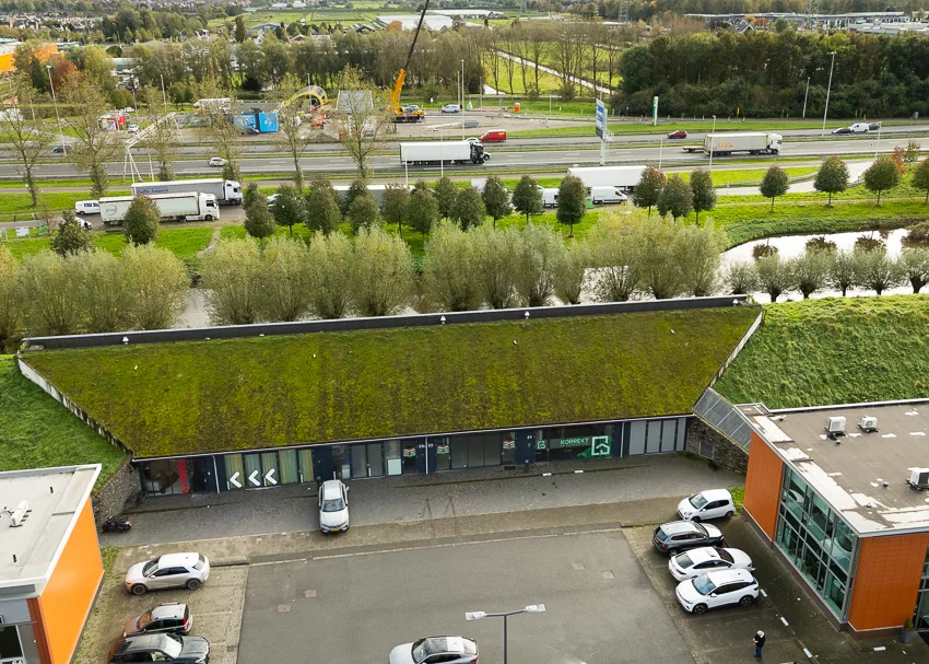 Lage, moderne bedrijfsunit aan de Mart Stamhof met een groen sedumdak en parkeergelegenheid ervoor.